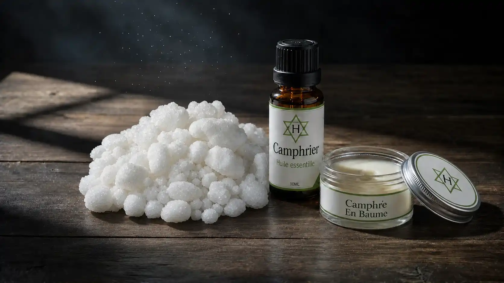 Camphre cristallisé, huile essentielle et baume — formes et précautions d'usage Camphre cristallisé blanc, flacon d'huile essentielle de camphrier et baume musculaire traditionnel — formes d'utilisation nécessitant des précautions strictes